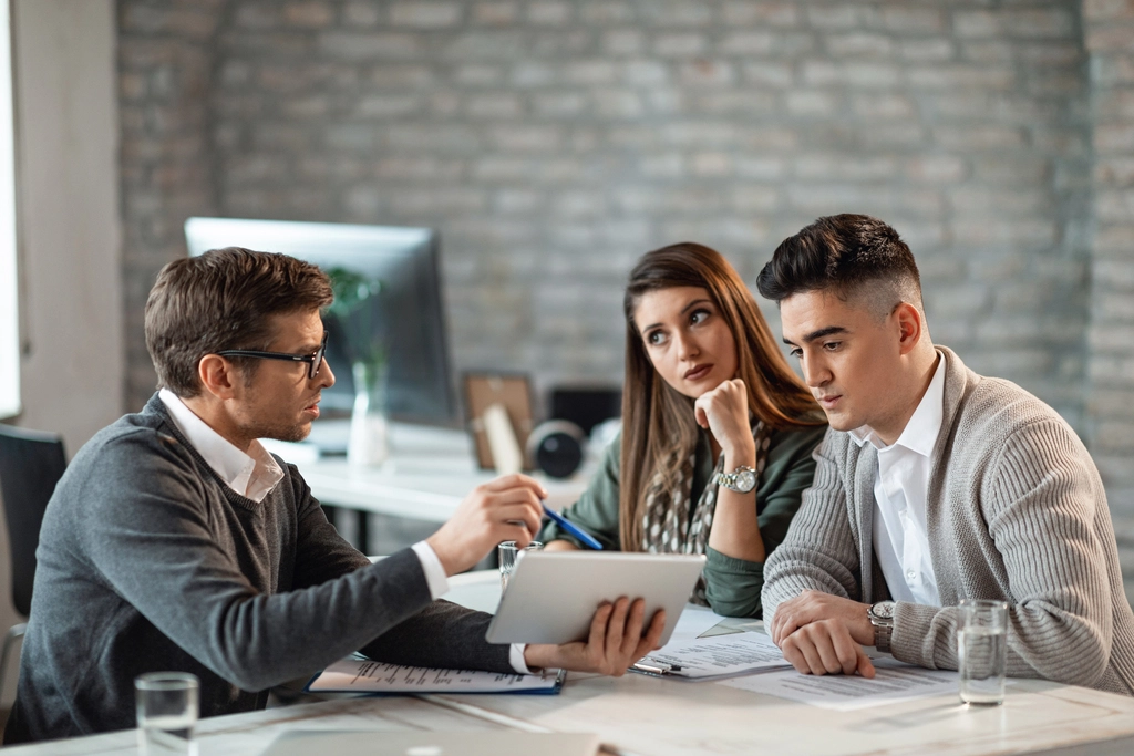 young-couple-using-digital-tablet-with-their-insurance-agent-consultations-office